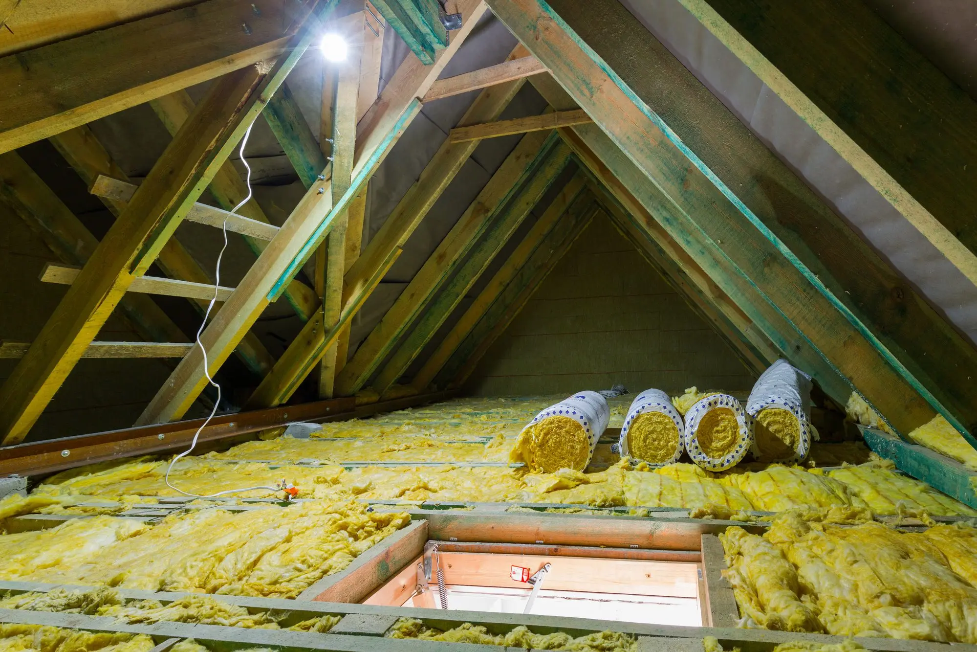 Insulated attic with exposed wooden beams and wiring.