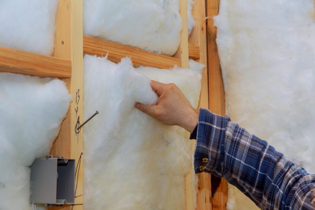 Worker in insulating rock wool insulation in wooden frame for future house walls for warm home,