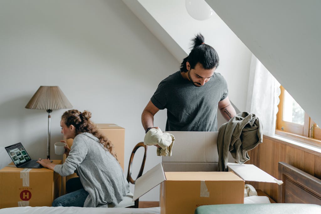 A couple moving into their new home, unpacking boxes and using a laptop for online browsing.