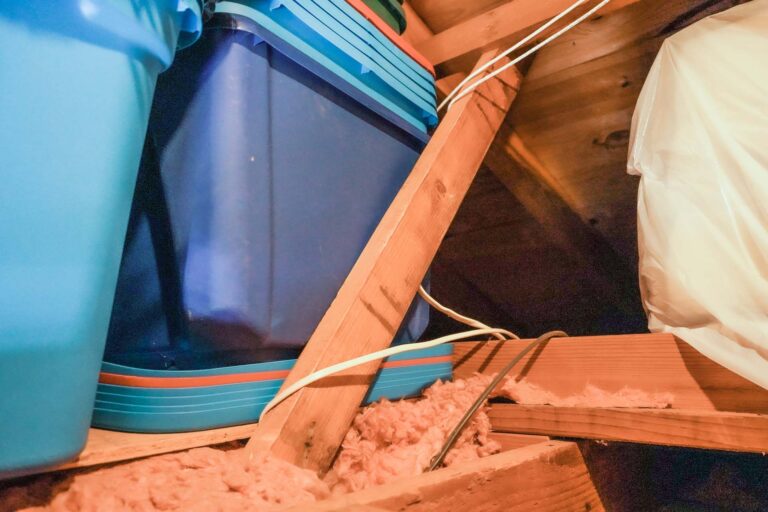 Storage bins stacked in a wooden attic space.
