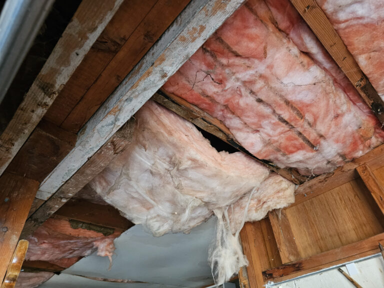 An open ceiling with the insolation clearly seen hanging from it.