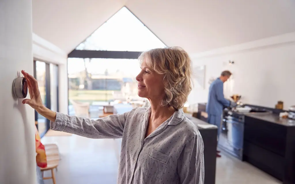Women changes the thermostat on the wall. Temperature changes are a sign you are losing energy due to poor insulation.
